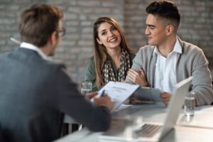 Un couple rencontrant un gestionnaire de patrimoine indépendant dans un bureau, discutant de leurs finances et de la gestion de leurs investissements.